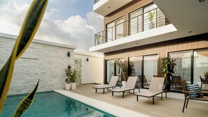 A modern outdoor pool area with lounge chairs and potted plants. - Ocean Dream Apartments E2-B4 (San Juan del Sur)