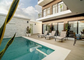 Ein moderner Poolbereich im Freien mit Liegestühlen und Kübelpflanzen.