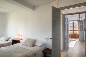 Een hotelkamer met twee bedden, een nachtkastje met een lamp en een houten bank.