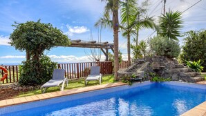A swimming pool with two lounge chairs, a wooden pergola, and a stone wall. - Ricardo House, a Home in Madeira (Calheta)