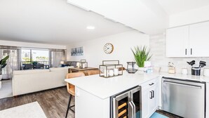 Une cuisine moderne avec des meubles blancs, un four encastré et un coin repas comprenant un canapé et une table.