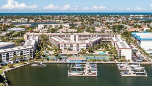 Un grand hôtel comprenant plusieurs bâtiments, une marina avec des bateaux, et une vue sur l’océan et le paysage urbain.