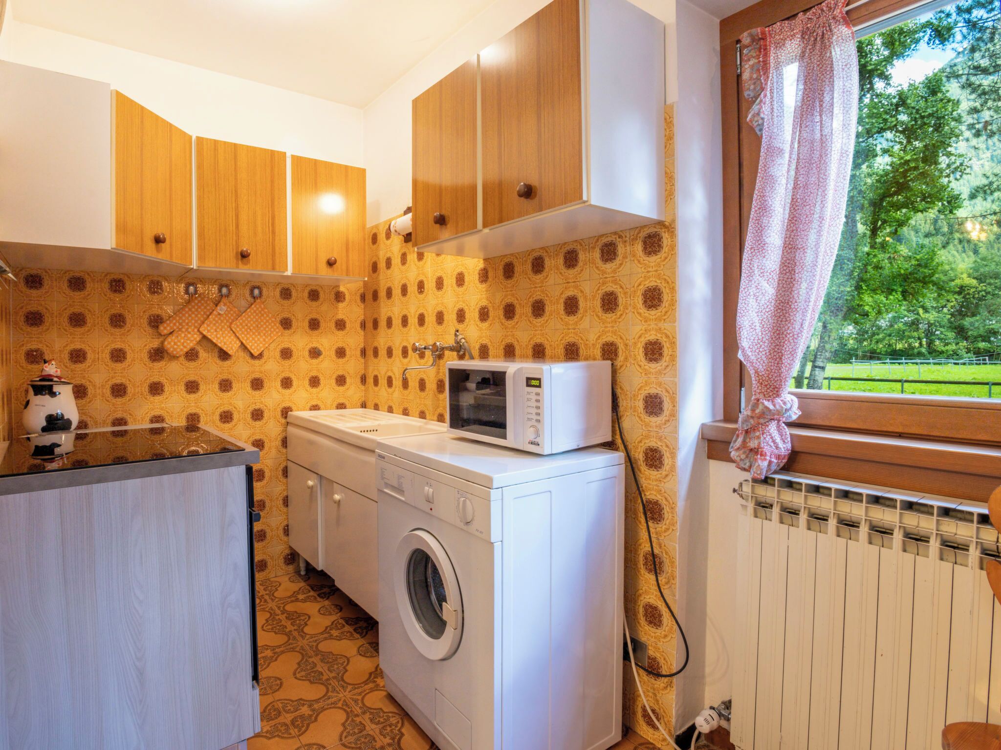 Eine kleine Küche mit Waschmaschine, Mikrowelle und Holzschränken.