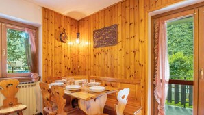 A wooden-paneled room with a dining table set for four, surrounded by wooden chairs. - Leonardi Terrace by Interhome (Campodolcino)