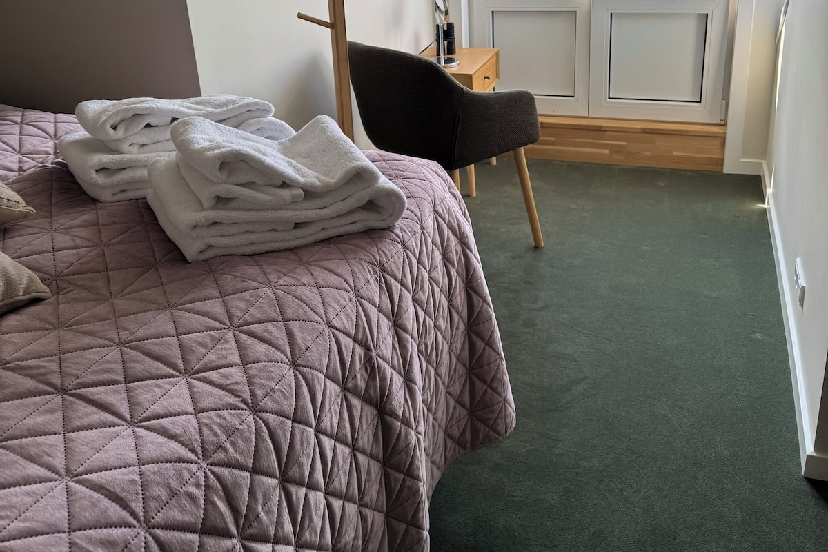 Une chambre à coucher avec un lit, une chaise, un porte-manteau et une vue sur l’extérieur.