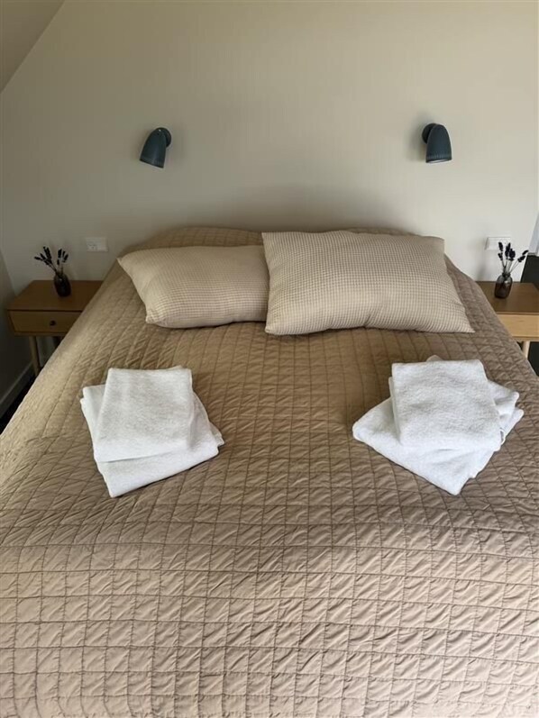 A neatly made bed with two pillows and two folded towels. - Bramslev Bakker Naturhotel (Hobro)