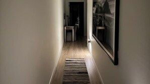A hallway with a wooden floor, a rug, and a framed picture on the wall. - Royal Suite Modern Studio Downtown on the Square (Bloomington)