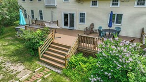 A wooden deck with a staircase leading to a door, surrounded by greenery and a small garden. - 4 BDR w/ Private Hot tub, Backyard and Deck! (Wells)