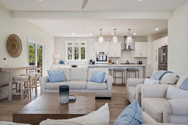 A spacious living area with a large sofa, a coffee table, and a kitchen in the background.