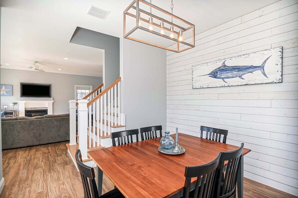 A dining area with a wooden table, black chairs, and a wall-mounted light fixture.