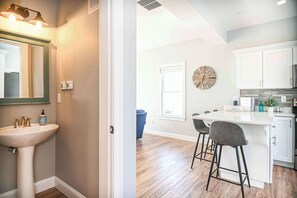Une cuisine moderne avec des meubles blancs, un plan de travail en bois et un coin bar avec des tabourets.