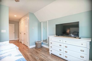 A bedroom with a bed, a dresser, a television, and a mirror.