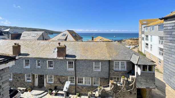 A stone building with multiple windows and a small garden area with outdoor furniture.