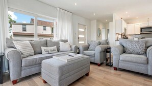 En moderne stue med grå sofaer, et sofabord og udsigt ud