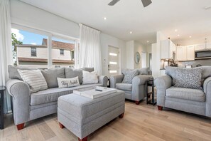 A modern living room with grey sofas, a coffee table, and a view of the outside.