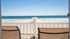 A balcony with wicker chairs overlooking a beach with waves and a clear sky. - Beachfront | 20 Steps to Long Sands | Ocean Views (York)