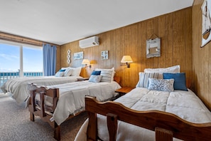 A hotel room with two wooden beds, a large window with a view, and a wooden wall panel. - Beachfront | 20 Steps to Long Sands | Ocean Views (York)