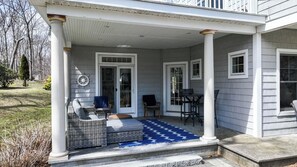 A covered porch with wicker furniture, a blue rug, and a ship wheel decoration. - Stunning 5 BDR, Walk to York Harbor Beach! (York)