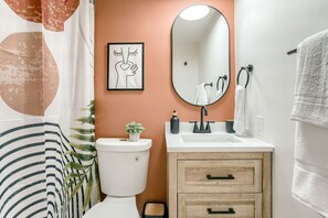 Une salle de bain équipée d’un WC, d’un lavabo, d’un miroir et d’un porte-serviettes.