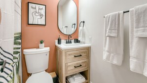 A bathroom with a toilet, sink, and wooden cabinet with drawers. - 5 min. to Lincoln's top attractions. Two-queens beds, pickleball & outdoor space (Lincoln)