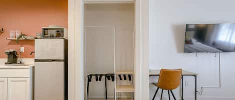 Habitación pequeña con kitchenette, cama, televisión y escritorio.