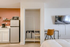 A compact room with a kitchenette, a bed, a TV, and a desk.