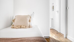 A bedroom with a bed, a white wall, and a wooden floor. - Blueground | République, concierge, courtyard view (Paris)