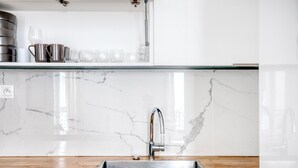 A kitchen with a stainless steel sink, white marble backsplash, and wooden countertop. - Blueground | République, concierge, courtyard view (Paris)