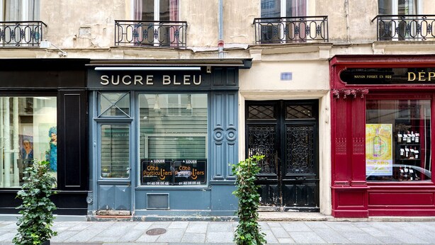 A storefront with a sign reading "SUCRE BLEU" and a red awning with a sign that reads "MAISON FONDEE EN 1822". - Blueground | Ile Saint Louis, nr Notre Dame (Paris)