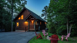 A log cabin with a porch, outdoor seating, and a fire pit.