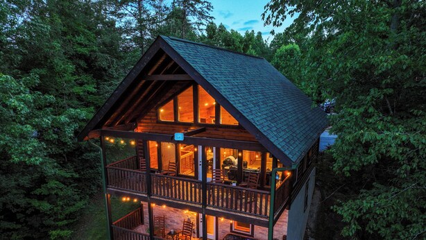 A cabin with a balcony, a hot tub, and a deck area.