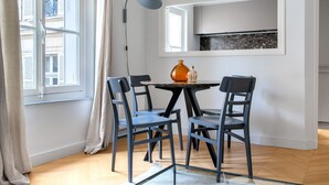 A dining area with a round table, four chairs, a floor lamp, and a window with curtains. - Blueground | Invalides, nr Rodin & Maillol Museums (Paris)