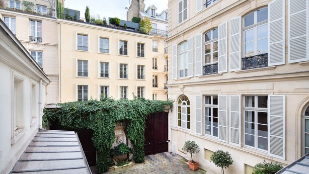 A narrow alleyway between buildings with a small garden area, stone steps, and a potted plant. - Blueground | Invalides, nr Rodin & Maillol Museums (Paris)