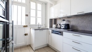 A modern kitchen with white cabinets, a stainless steel refrigerator, a dishwasher, and a countertop with a coffee maker and toaster. - Blueground | Faisanderie, a/c, nr Eiffel Tower (Paris)
