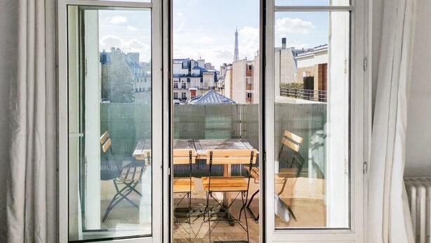 A room with a large window overlooking a cityscape, including a prominent tower. - Blueground | Faisanderie, a/c, nr Eiffel Tower (Paris)