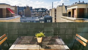 A rooftop terrace with a table and chairs, a potted plant, and a view of the Eiffel Tower. - Blueground | Faisanderie, a/c, nr Eiffel Tower (Paris)