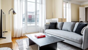 A modern living room with a grey sofa, a black coffee table, and a large window with curtains. - Blueground | Faisanderie, a/c, nr Eiffel Tower (Paris)