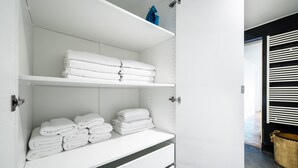 A white storage unit with shelves holding folded towels. - Blueground | Saint Germain, nr the Sorbonne (Paris)