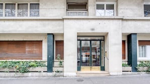 A two-story building with a central entrance featuring a glass door and a small set of steps. - Blueground | Auteuil, elevator & concierge (Paris)