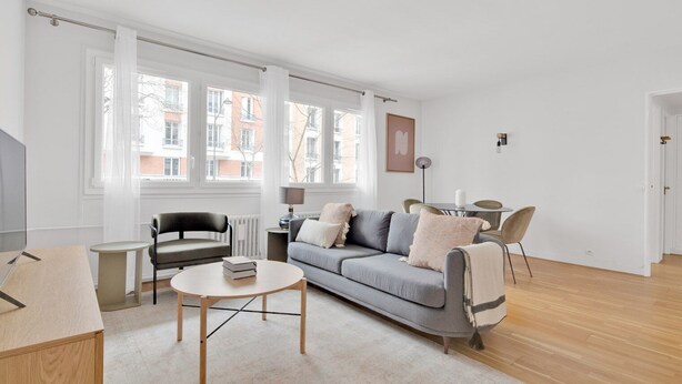 A modern living room with a grey sofa, a round coffee table, a black armchair, and a small side table. - Blueground | Auteuil, elevator & concierge (Paris)