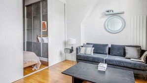 A modern living room with a grey sofa, a coffee table, a lamp, and a large mirror on the wall. - Blueground | Miromesnil, nr Parc Monceau (Paris)