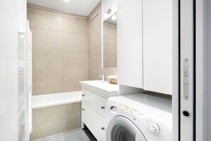 A modern bathroom with a white vanity, a built-in washing machine, and a large mirror. - Blueground | Trocadero, roof, canopy (Paris)
