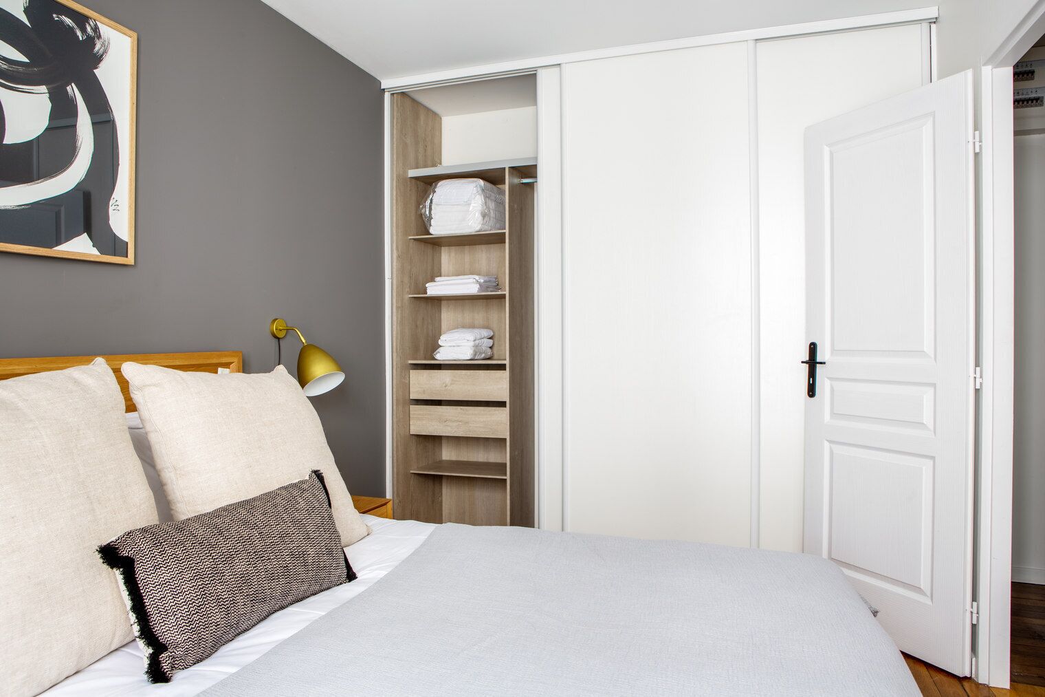 Un dormitorio con cama, almohadas, lámpara de noche, armario y puerta.