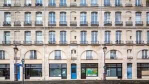 Ein mehrgeschossiges Gebäude mit einheitlicher Fassade, das Bogenfenster und Balkone zeigt.