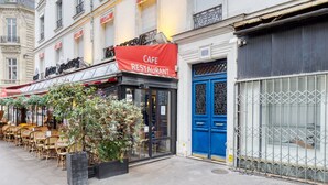 A cafe restaurant with outdoor seating, a blue door, and a red awning. - Blueground | Arc de Triomphe, nr shops (Paris)