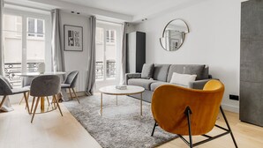 Un salon moderne avec un canapé gris, une table basse ronde et deux fauteuils.