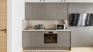 Une cuisine moderne avec des meubles gris, un four encastré, un four à micro-ondes, un grille-pain et une machine à café.