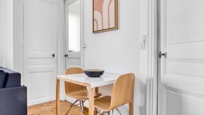 A dining area with a white table, two wooden chairs, and a bowl on the table. - Blueground | St Placide, balcony, nr Bon Marché (Paris)