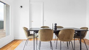 Un espace repas comprenant une table rectangulaire, six chaises et un tapis de couleur claire.
