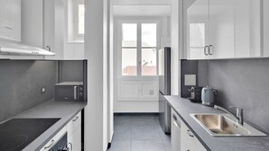Una cocina moderna con horno empotrado, microondas y pileta de acero inoxidable.